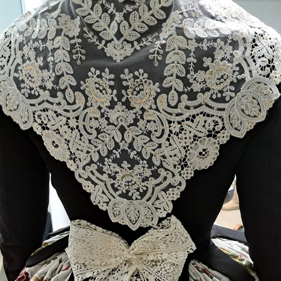 Manteleta blanca de encaje presentada sobre maniquí negro