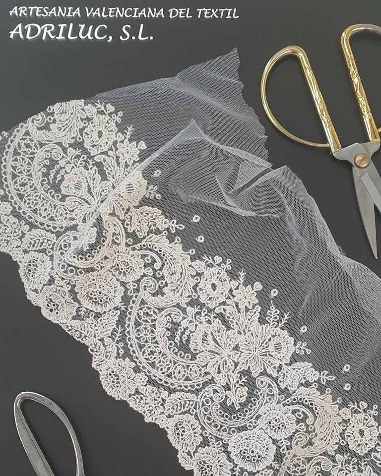 Panel de encaje floral extendido junto a unas tijeras de taller