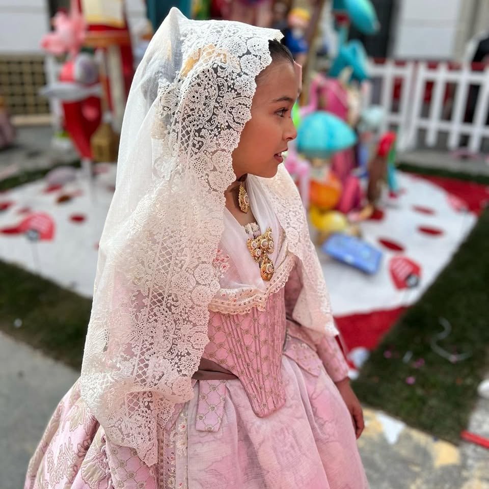 Niña con indumentaria valenciana rosa y mantilla blanca