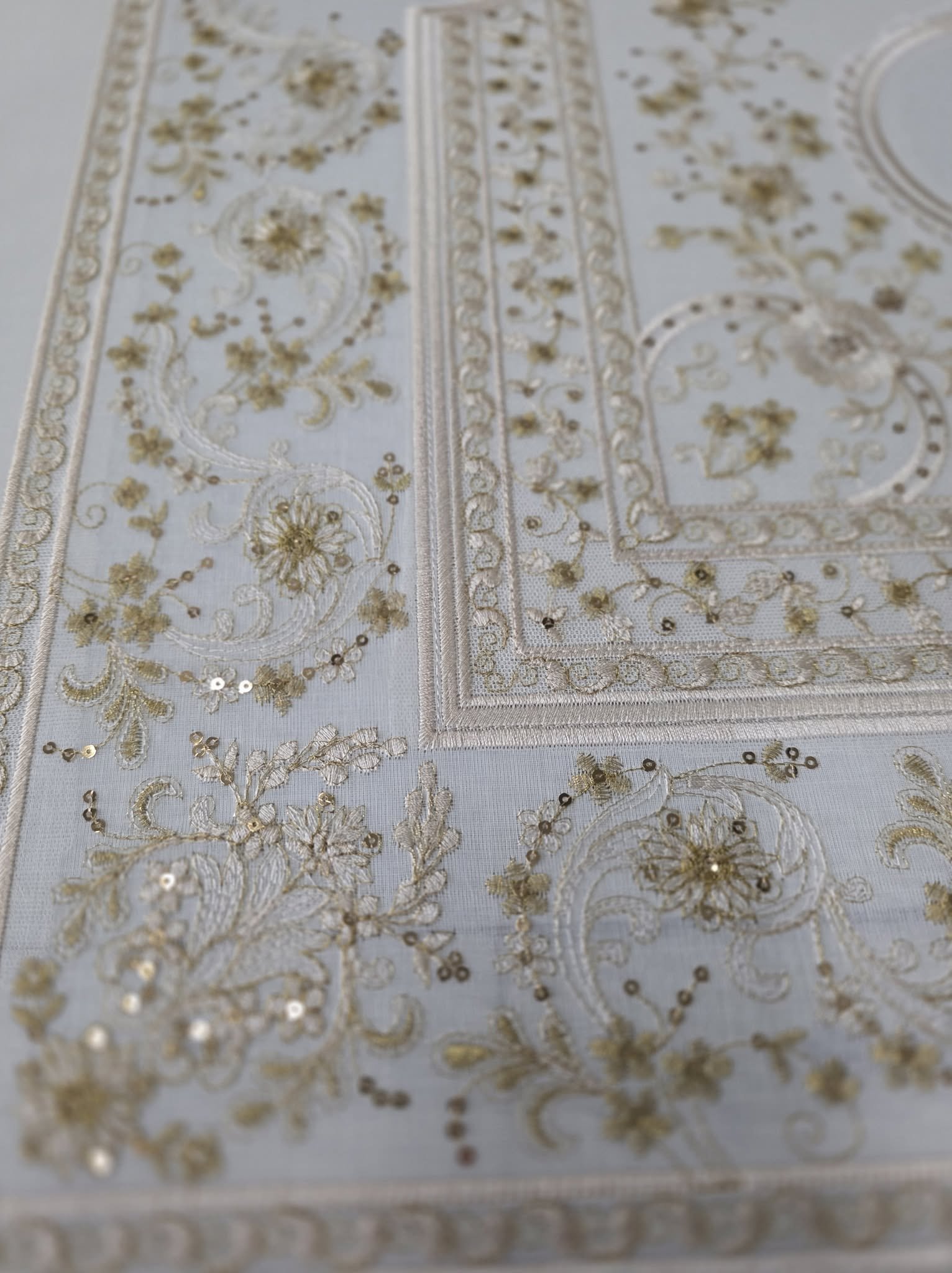 Detalle de bordado floral dorado con pequeñas aplicaciones