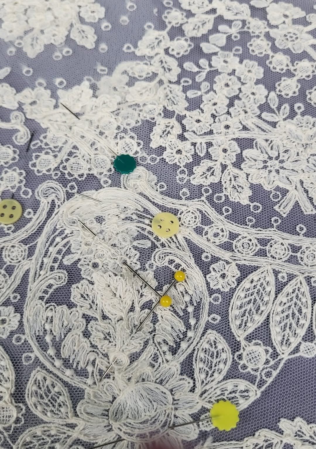 Detalle de encaje blanco sujeto con alfileres durante el proceso de acabado